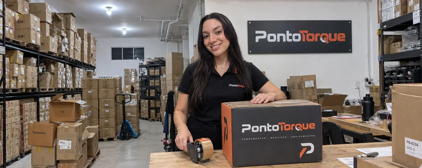 Atendente da Ponto Torque no estoque da loja, fechando uma caixa da marca sobre a bancada de expedição